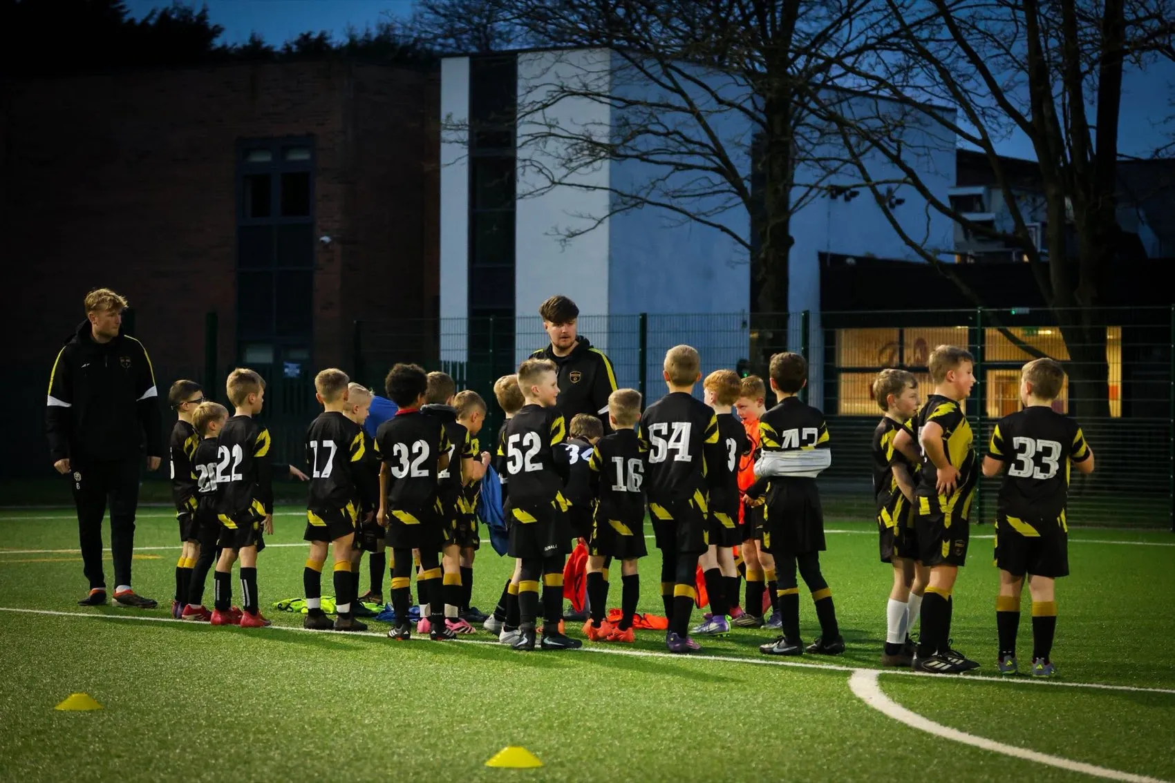 A DNA Academy coach talking to a group of young players on the pitch