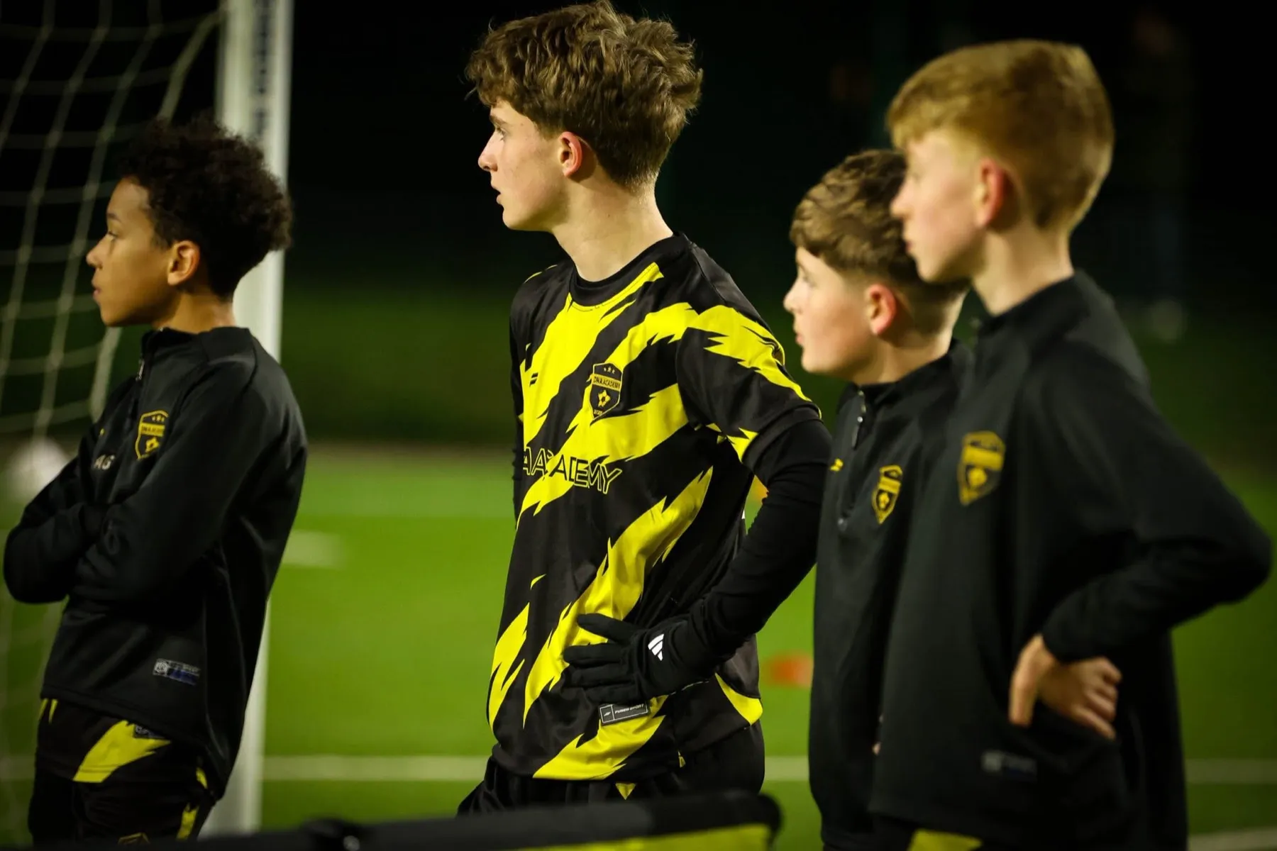 DNA Academy players in the black and yellow kit during a floodlit training session